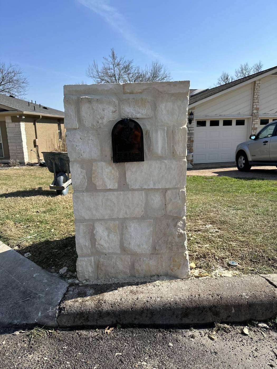 Chopped limestone mailbox column with arched mail slot at the curb