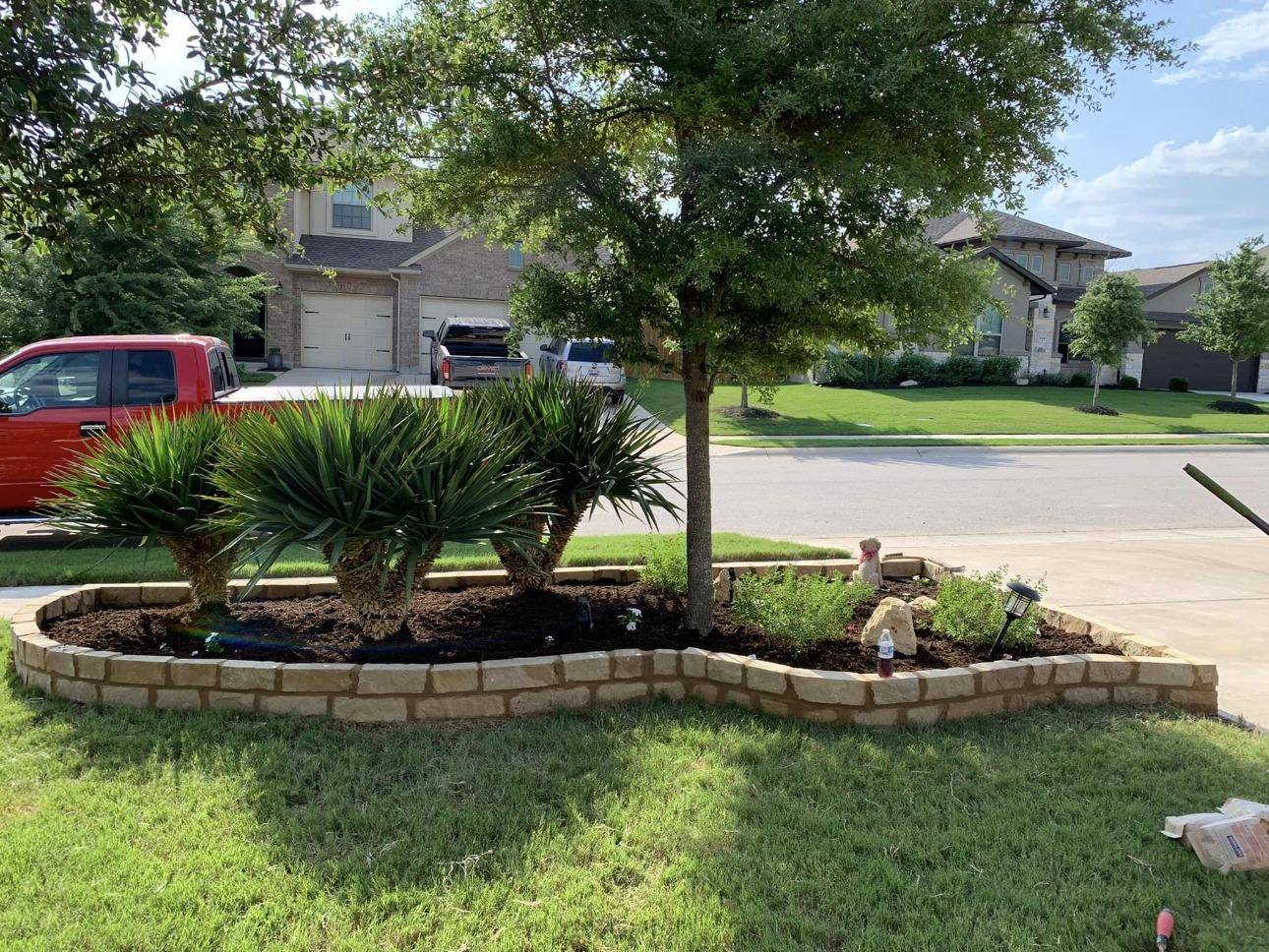 Curved stone border flower bed with palms and shrubs in a front yard