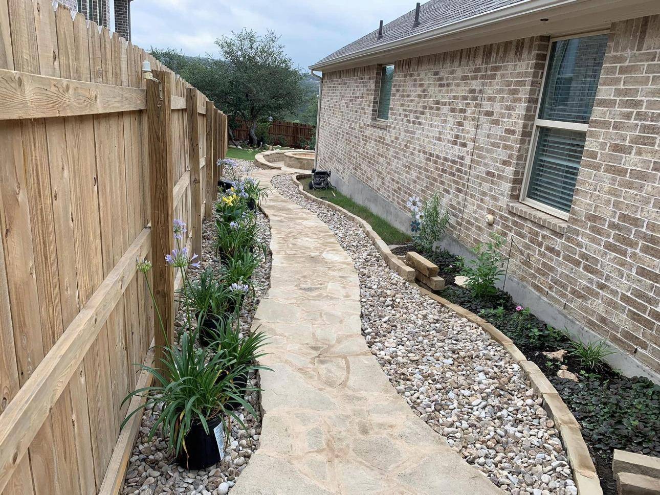 Flagstone side-yard walkway with stone-edged planting beds and decorative rock