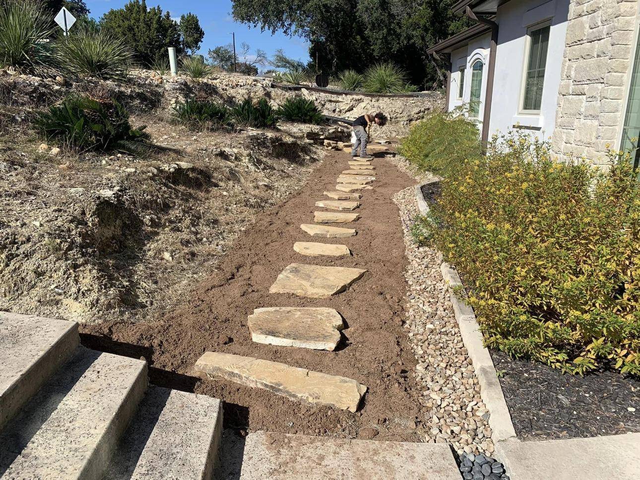 Flagstone stepping path installed up a sloped side yard beside stone steps