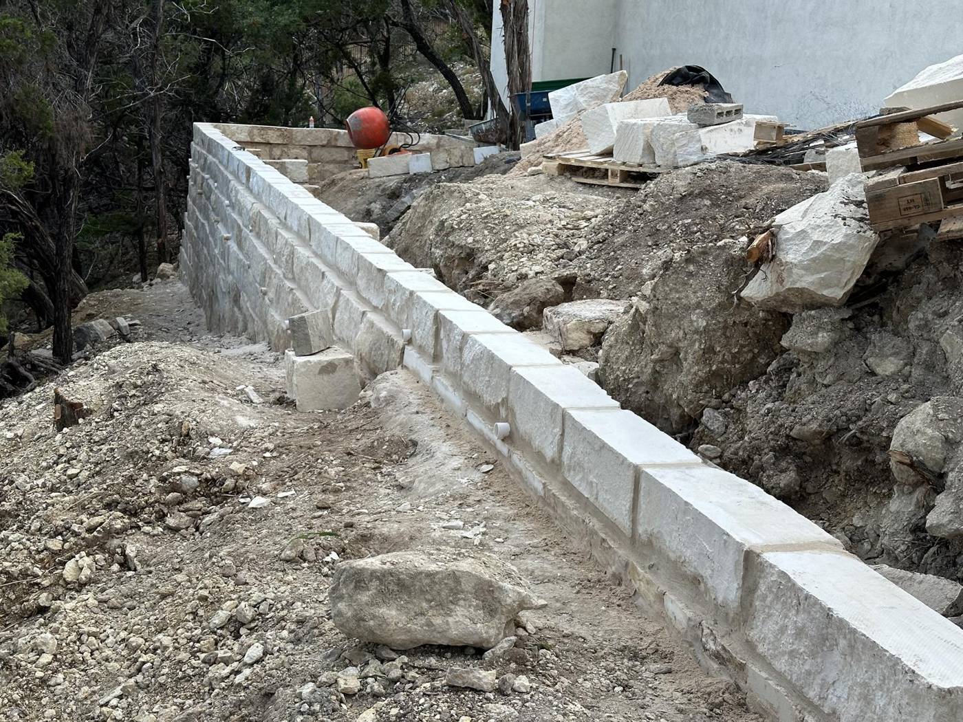 Limestone block retaining wall under construction on a sloped lot