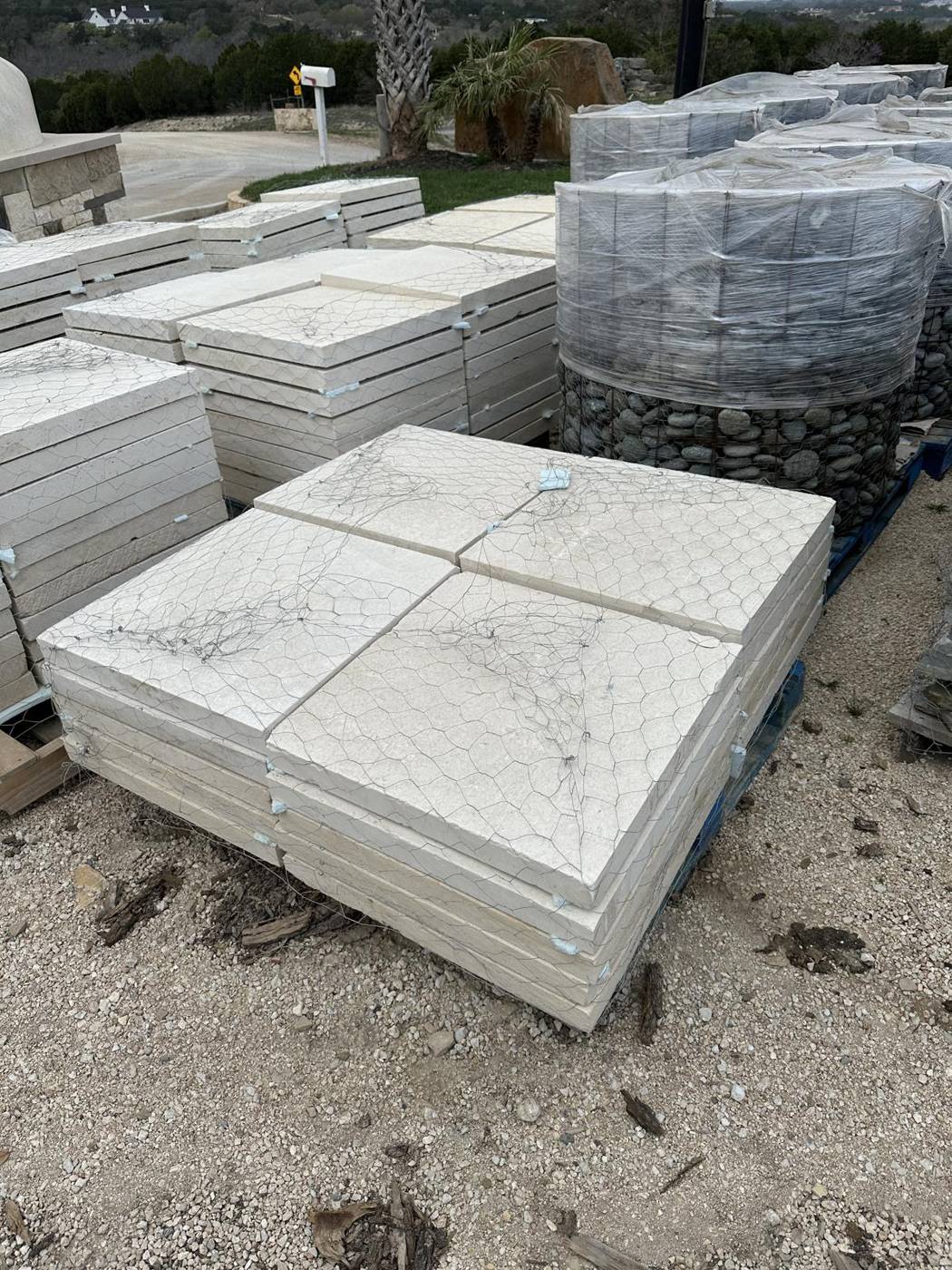 Pallets of limestone pavers and river rock at the stone yard