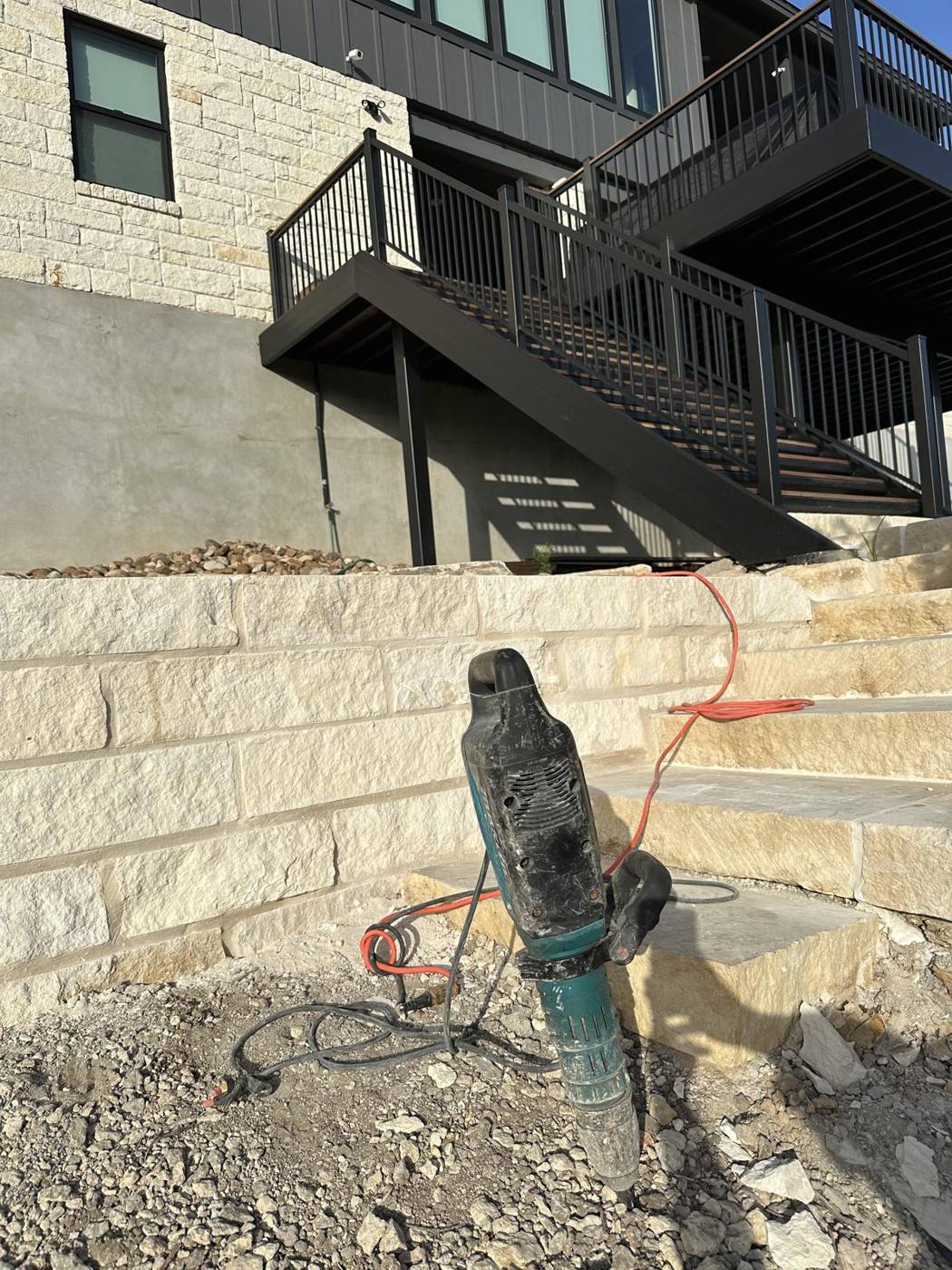 Limestone block retaining wall and steps below an exterior staircase on a modern home