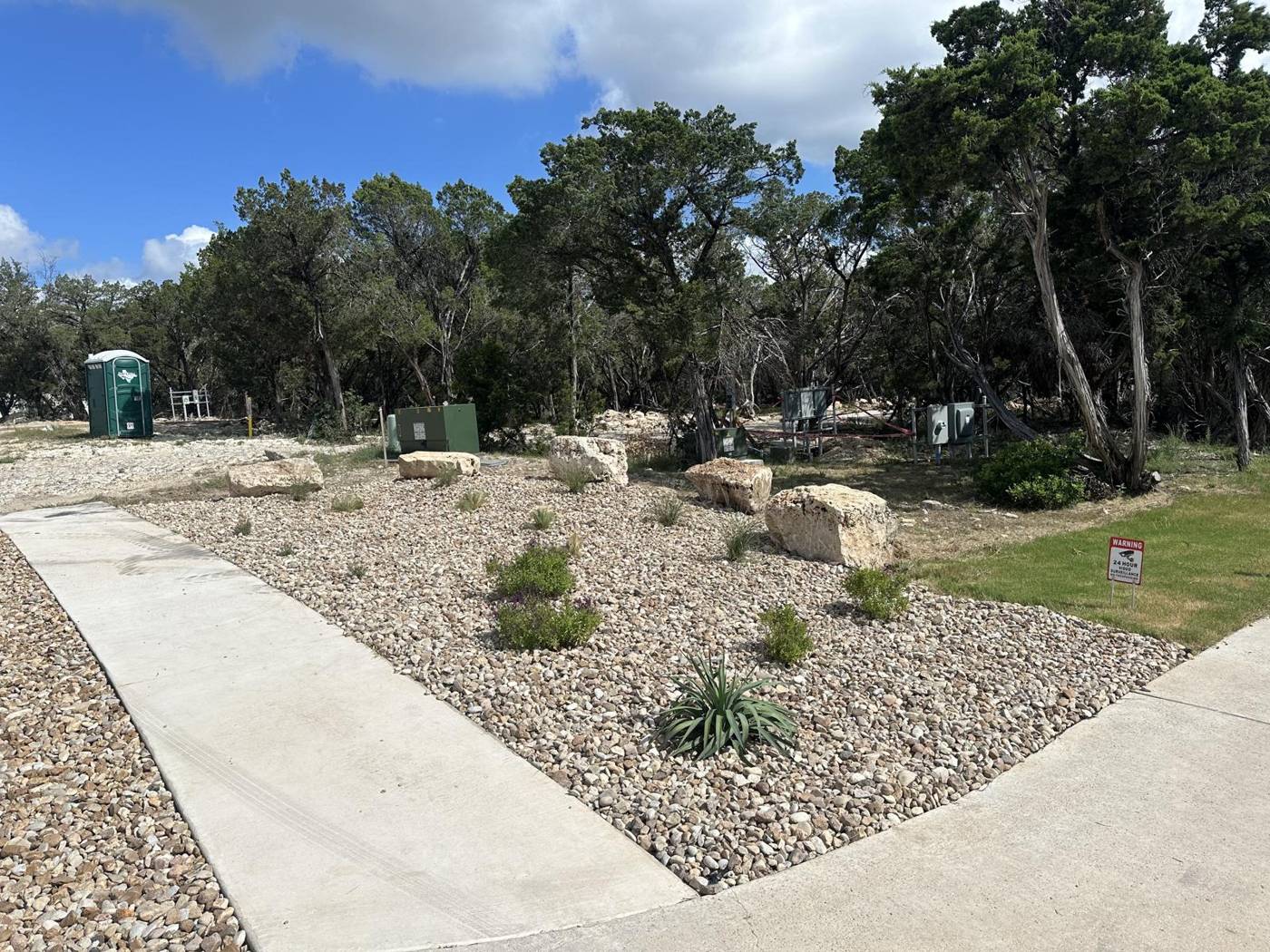 Native plant xeriscape installation with boulders and river rock under live oaks