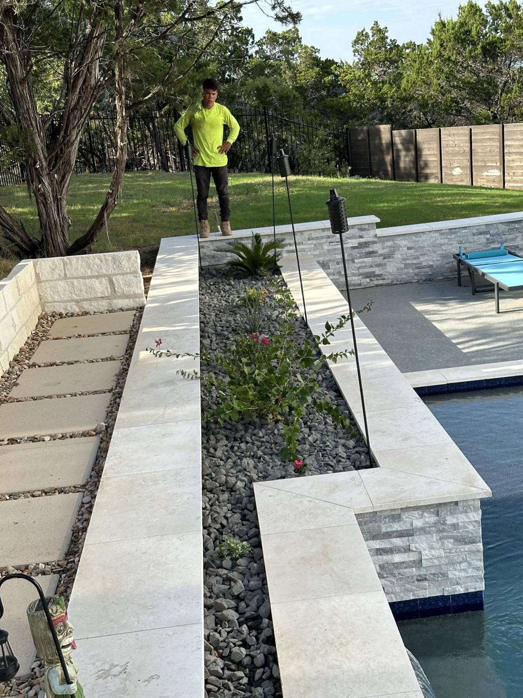 Pool hardscape with limestone coping, stepping pavers and a river rock planter bed
