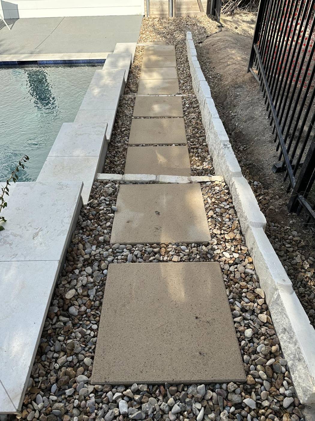 Poolside paver walkway set in river rock with limestone edging