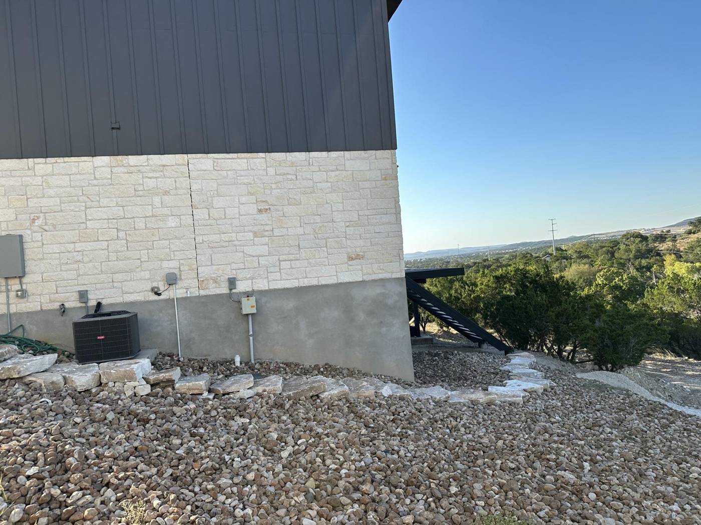 River rock landscaping with boulder border around a modern Hill Country home