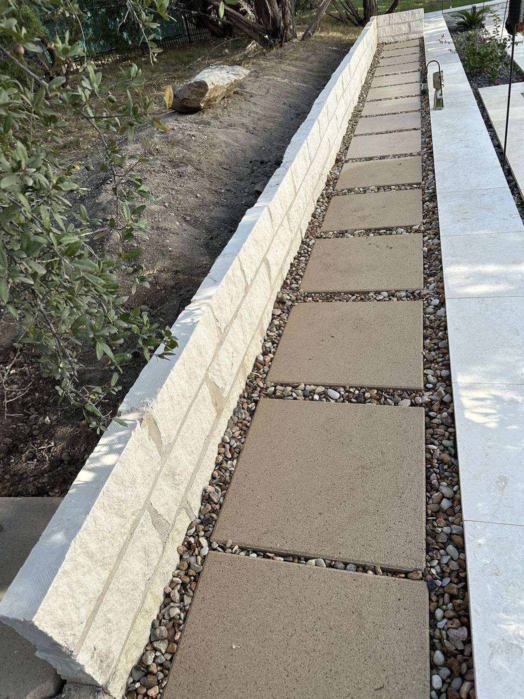 Stepping-stone paver walkway set in river rock between limestone border walls