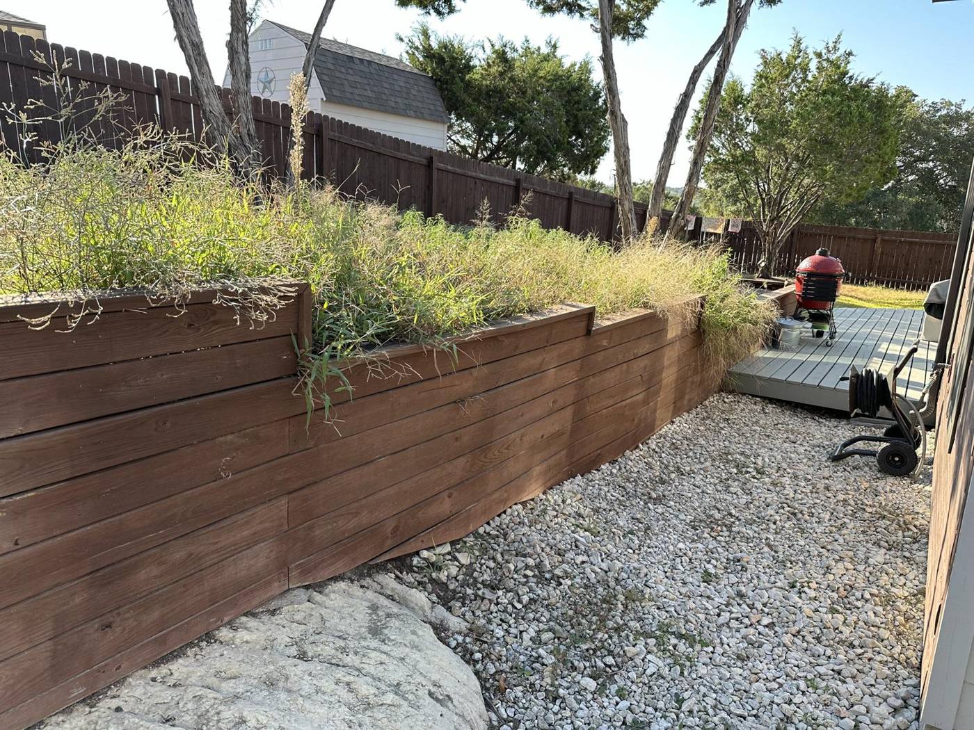 Timber retaining wall with native grasses above a crushed gravel side yard
