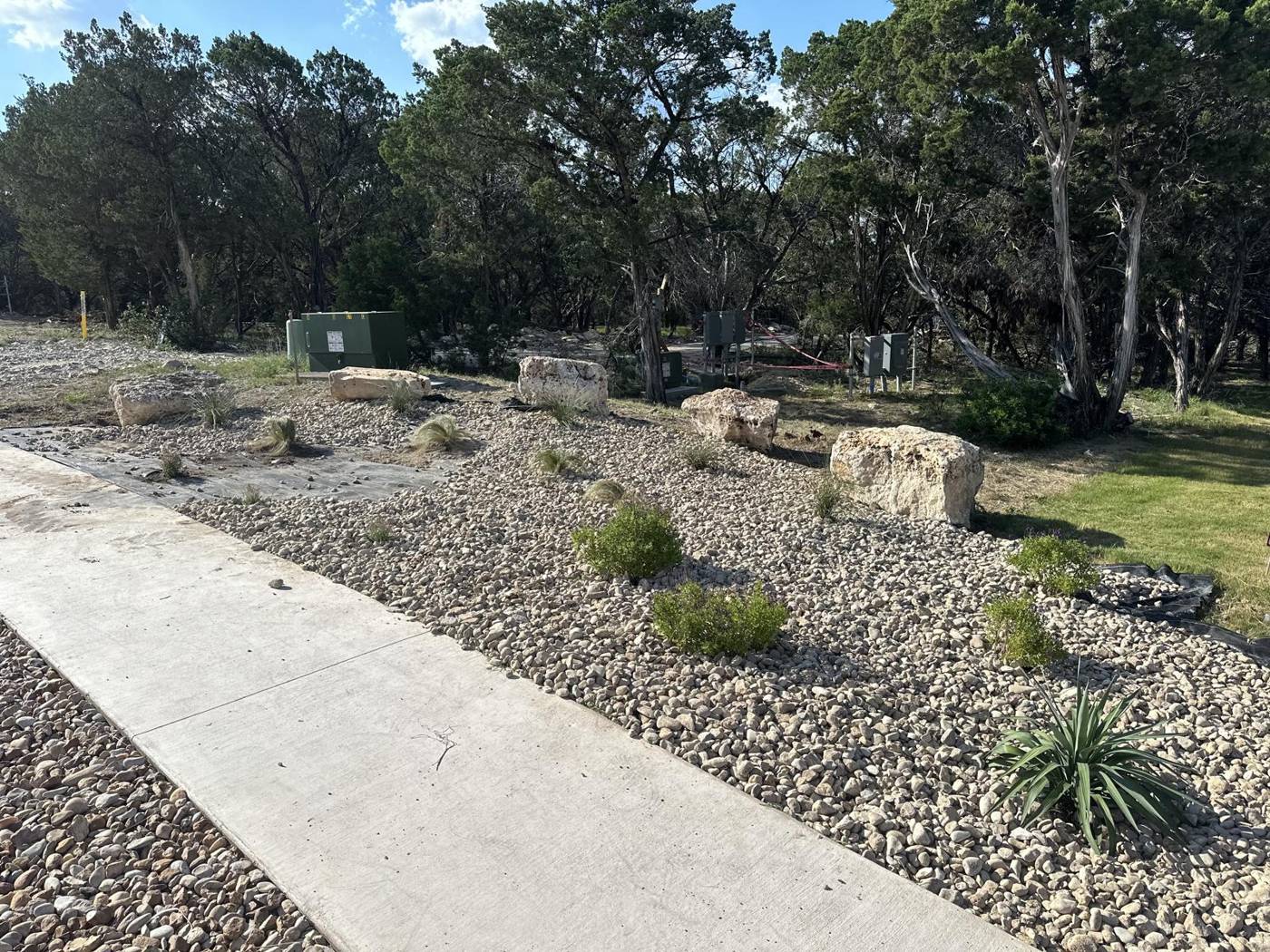 Xeriscape along a driveway with limestone boulders, agave and river rock